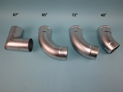 Vier metallische Rohrbogen mit verschiedenen Winkeln (87°, 85°, 72° und 40°) nebeneinander angeordnet. Jeder Bogen hat ein glänzendes Finish und unterschiedliche Krümmungen, auf einem hellblauen Hintergrund.