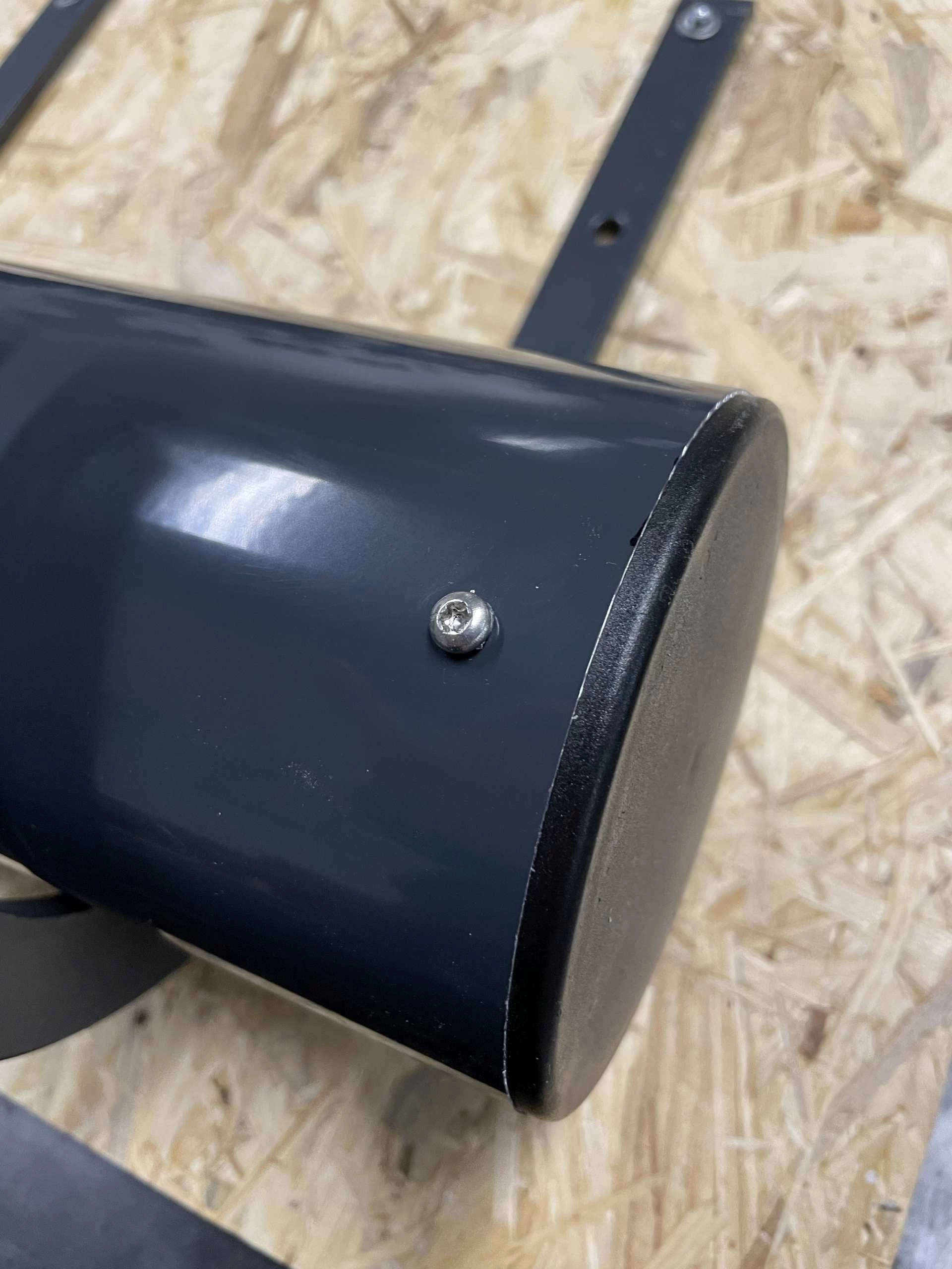 Nahaufnahme einer Torx-Linsenkopfschraube aus Edelstahl, die ein schwarz lackiertes Rohr mit einem silbernen Aluminiumteil verbindet, saubere Montage auf Werkstattplatte sichtbar.