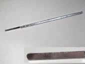 Ein langer, schmaler Metallstab mit einem flachen Ende, der als Werkzeug dient. Die Oberfläche ist glänzend und zeigt keine sichtbaren Marken oder Beschädigungen. Der Hintergrund ist einheitlich und hell.