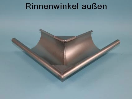 Ein Rinnenwinkel aus Metall ist in der Mitte v-förmig gefaltet mit zwei abgerundeten Seiten. Er besteht aus glänzendem, silbernem Material und steht auf einer blauen Fläche. Darauf steht der Text -Rinnenwinkel außen-.
